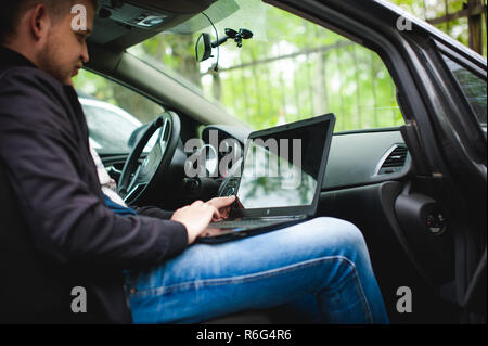 Professionelle Mann mit Laptop im Auto tunes tuning Control-System, Aktualisierung von Software, Zugang durch Computer, sitzen in der Kabine Stockfoto