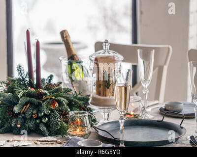 Nahaufnahme der Tabelle für das Weihnachtsessen im Wohnzimmer serviert. Schneereiche Winter im Fenster im Hintergrund. Schöne serviert Tabelle mit Dekorationen, Kerzen, Tannenzweigen. Urlaub Stockfoto