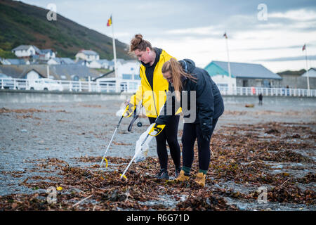 Zwei junge Frauen, die freiwilligen Helfer, die Kursteilnehmer von Aberystwyth University, sammeln Müll und Abfälle aus Kunststoffen auf der South Beach gewaschen in Aberystwyth in den Nachwehen des Sturms Callum. Oktober 2018, Wales UK Stockfoto