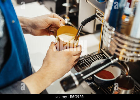Nahaufnahme von Barista dampfende Milch in den Krug mit Kaffeemaschine. Stockfoto