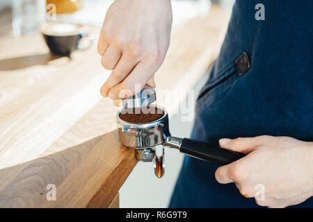 Barista Hände halten portafilter und Kaffee tamper einen Espresso. Stockfoto