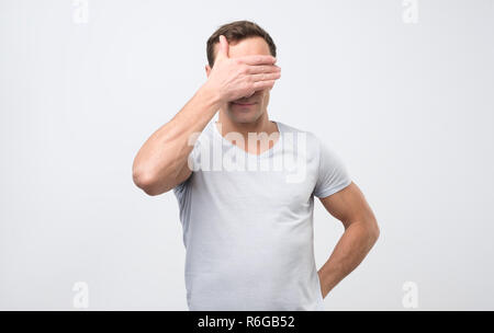 Nicht erkennbare Mann mit die Augen und fühlen sich schämen, sich gegen leere studio Wand Stockfoto