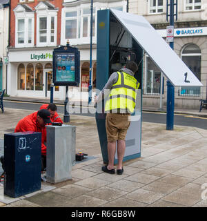 Handwerker installieren einer neuen High-tech Digital Advertising Display Kiosk auf der Straße in Aberystwyth Wales UK Stockfoto