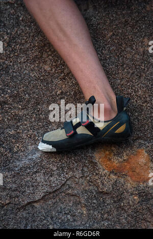 Nahaufnahme von einem Männchen Bein und Fuß in Klettern Schuhe greifen auf die scharfen Oberfläche einer Hampi Boulder, Indien. Stockfoto