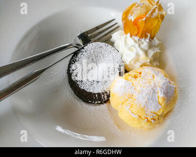 Eis auf weiße Platte/mango Eis gelb cookies Schokolade und Kap Stachelbeeren mit Puderzucker auf Ansicht von oben Stockfoto