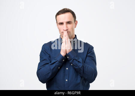 Verzweifelten jungen Mann mit gefalteten Händen, um Hilfe zu bitten Stockfoto