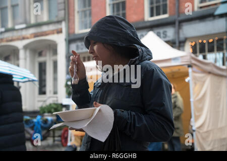 An einem regnerischen Wintertag auf einem Bauernmarkt in Manhattan's Historic South Street Seaport, eine Frau Proben einige Italienische Küche. Stockfoto