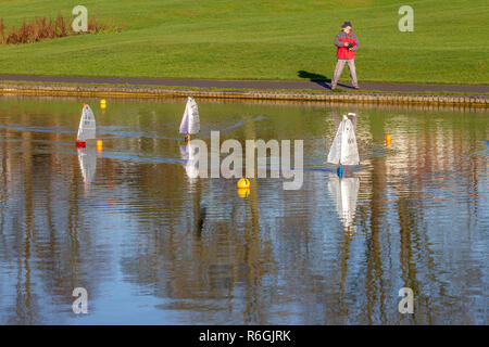 Mitglieder von Abington Park model Boat Club segeln ihre Radio kontrollierten Modellen, die auf den Park See auf einem kalten helle Winter morgen. Stockfoto