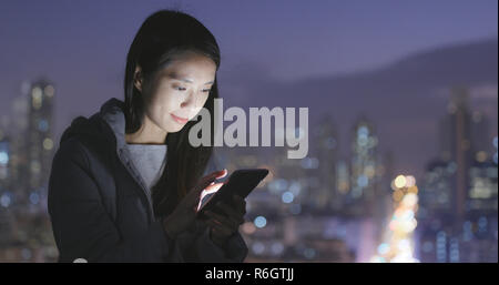 Frau mit Handy über die Stadt bei Nacht Stockfoto