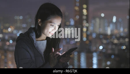 Frau mit Handy über die Stadt bei Nacht Stockfoto