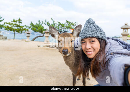 Junge Frau von selfie mit Rotwild in Itsukushima Stockfoto