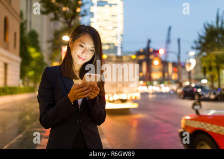 Junge Geschäftsfrau, die Nutzung von Mobiltelefonen in Tokyo City Stockfoto