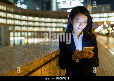 Geschäftsfrau, die Nutzung von Mobiltelefonen in Tokio City bei Nacht Stockfoto