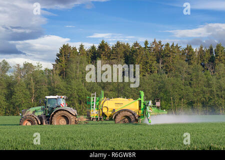 Bauer im Traktor spritzen Insektizide Herbizide //Pestizide über auf dem Feld mit der gezogenen Feldspritze im Frühjahr Stockfoto