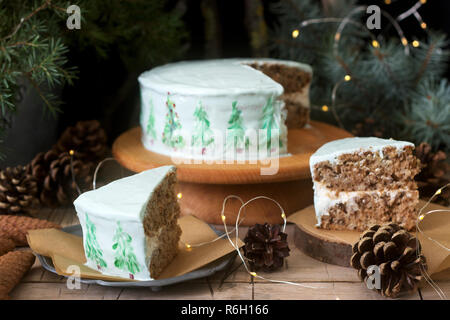 Festliche Kuchen mit gemalten Weihnachtsbaum auf einem dunklen Hintergrund der Zweige und Zapfen dekoriert. Im rustikalen Stil. Stockfoto