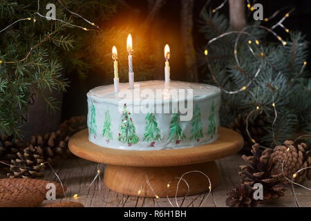 Festliche Kuchen mit gemalten Weihnachtsbaum auf einem dunklen Hintergrund der Zweige und Zapfen dekoriert. Im rustikalen Stil. Stockfoto