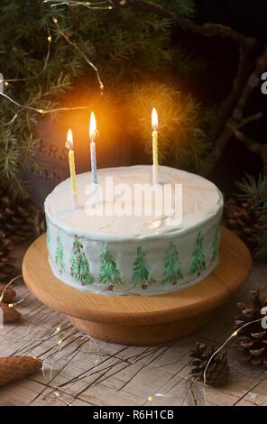 Festliche Kuchen mit gemalten Weihnachtsbaum auf einem dunklen Hintergrund der Zweige und Zapfen dekoriert. Im rustikalen Stil. Stockfoto