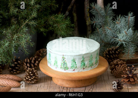 Festliche Kuchen mit gemalten Weihnachtsbaum auf einem dunklen Hintergrund der Zweige und Zapfen dekoriert. Im rustikalen Stil. Stockfoto