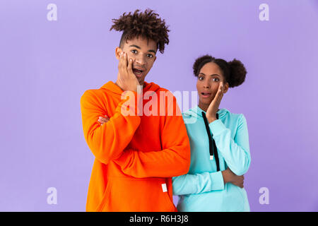 Foto von schockiert afrikanische amerikanische Bruder und Schwester schreien und berühren Gesicht über violette Hintergrund isoliert Stockfoto