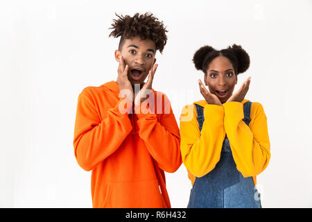 Bild von Angeregten afrikanische amerikanische Paar in bunten Kleidern, die schreien und berühren Wangen auf weißem Hintergrund Stockfoto