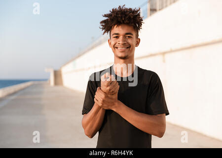 Bild der hübschen jungen Kerl Sportsman posiert im Freien am Strand. Stockfoto