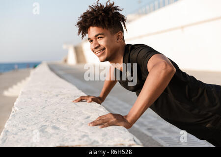 Bild der hübschen jungen Kerl Sportler machen Übungen im Freien am Strand. Stockfoto