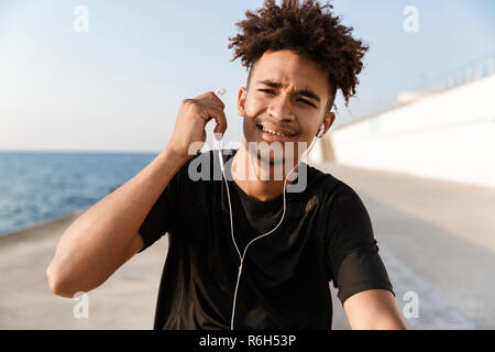 Nahaufnahme eines jungen afrikanischen Teenager am Strand, Musik hören mit Kopfhörern Stockfoto