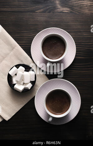 Zwei Tassen Kaffee mit Würfeln Zucker auf den Tisch, von oben Stockfoto