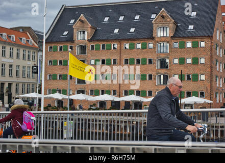 Radfahrer auf Inderhavnsbroen (Inner Harbour Bridge), mit einer konservierten Nyhavn Lager im Hintergrund, Nyhavn, Kopenhagen, Dänemark, Skandinavien Stockfoto