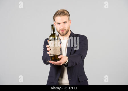 Möchten Sie dies zu versuchen. Sommelier bieten eine Flasche Wein. Professionelle Weindegustation Konzept. Mann Anzug mit Flasche Wein in der Hand. Sommelier stattlichen überzeugter Kerl auf grauem Hintergrund. Stockfoto