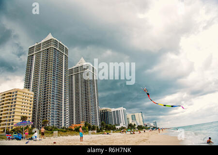 Miami South Beach. Leute spielen mit Kite am Sandstrand am Meer, Meer, Palmen, Hotel oder Häuser Gebäude an bewölkten Himmel Hintergrund, Florida. Reisen und Urlaub Stockfoto