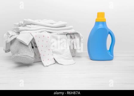 Mit flüssigem Waschmittel Flasche vor dem Hintergrund der Korb mit Baby Kleidung. Stockfoto