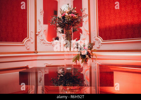 Hotel Lobby in roter Farbe, mit einer großen Vase mit Blumen dekoriert. Stockfoto