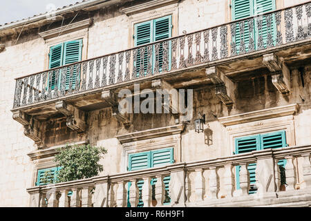 Die Fassade eines gewöhnlichen alten Gebäude mit Fenstern und Balkons in Montenegro. Fenster geschlossen auf der Rollläden. Traditionelle Gehäuse. Stockfoto