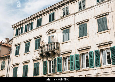 Die Fassade eines gewöhnlichen alten Gebäude mit Fenstern und einem Balkon in Montenegro. Einige Fenster sind durch die Fensterläden geschlossen. Traditionelle Gehäuse. Stockfoto