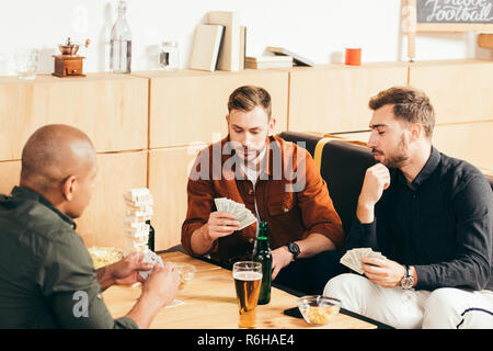 Multikulturelle Männer spielen Karten und verbringen die Zeit zusammen im Cafe Stockfoto