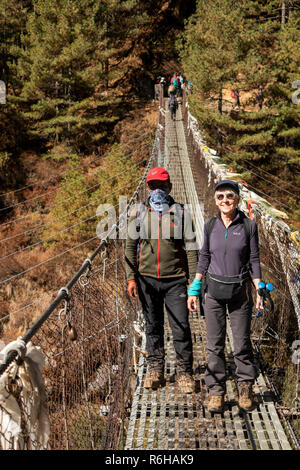 Nepal, Jorsale (Thumbug), Senior Trekker und Sherpa Guide Kreuzung metall Hängebrücke über Dudh Khosi Stockfoto