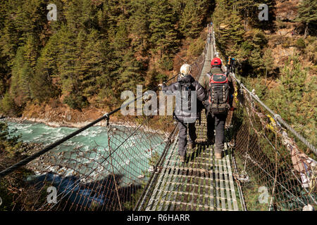 Nepal, Jorsale (Thumbug), Senior Trekker und Sherpa Guide Kreuzung metall Hängebrücke über Dudh Khosi Stockfoto