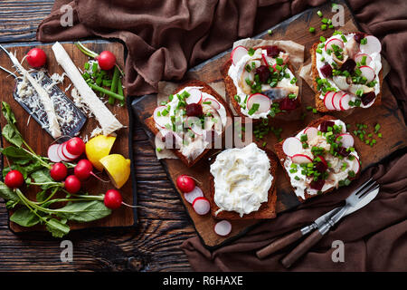 Smorrebrod - Dänische offen stehen Sandwiches mit geräucherter Makrele Schichten, Creme gemischt mit geriebenem Meerrettich, Rote Beete, frische Radieschen, Zwiebeln auf einem dunklen Cu Stockfoto