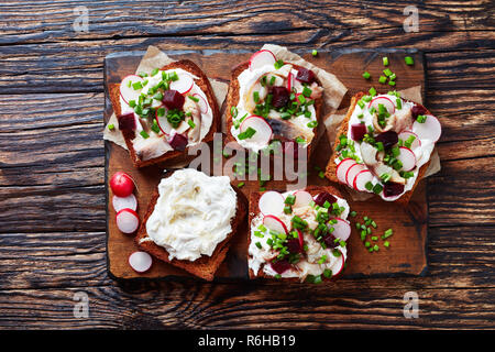 Smorrebrod - Dänische offen stehen Sandwiches von Roggenbrot, geräucherte Makrele, Scheiben, Creme gemischt mit geriebenem Meerrettich, Rote Bete, frische Radieschen, Zwiebel o Stockfoto