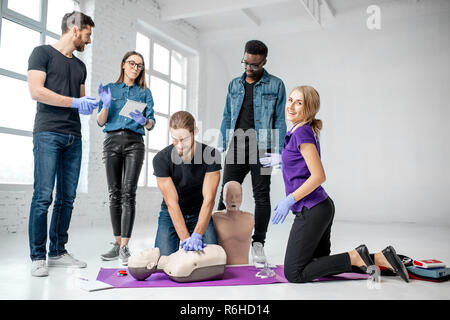 Eine Gruppe der Jungen praktizierenden künstliche Atmung mit Ausbilder und medizinische Dummies während der Erste Hilfe training Zuhause zu machen Stockfoto