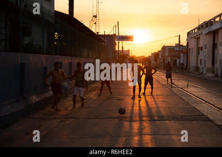 Silhouetten der kubanischen Jungen spielen Straßenfußball, wie die Sonne hinter Ihnen in Cienfuegos Kuba Stockfoto
