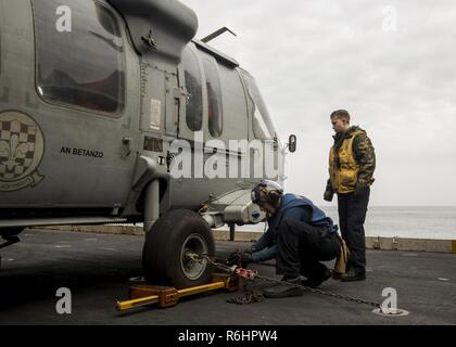 WESTERN PACIFIC (16. Mai 2017) Flieger Robert Young, der tabares, Florida, Links, und der Luftfahrt Bootsmann Mate (Handling) 3. Klasse Sarah-Katie Prielipp, von Ann Arbor, Michigan, Keil und Kette einem MH-60S Sea Hawk vom Hubschrauber aus Meer Combat Squadron (HSC) 4 "Schwarzen Ritter" auf ein Flugzeug Aufzug an Bord der Nimitz-Klasse Flugzeugträger USS Carl Vinson (CVN 70). Die US-Marine hat die Indo-Asia - Pazifik routinemäßig für mehr als 70 Jahre patrouillierten die Förderung von Frieden und Sicherheit in der Region. Stockfoto