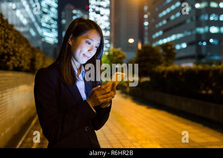 Geschäftsfrau, die Verwendung von Handys in Tokyo City Stockfoto