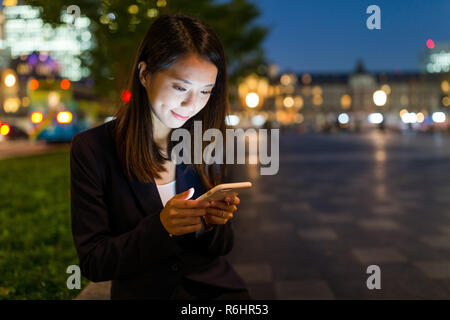 Junge Geschäftsfrau, die Verwendung von Handys in Tokyo City Stockfoto