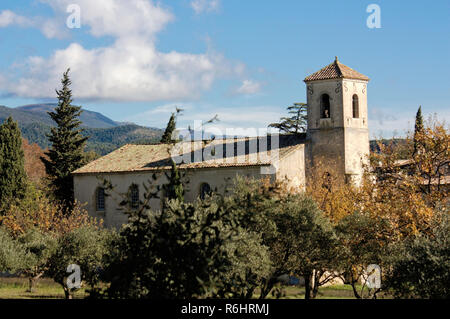 Blick auf ein altes Dorf im Luberon region, Südfrankreich. Alte Kirche und Häuser mit Bäumen und Sonnenschein. Stockfoto