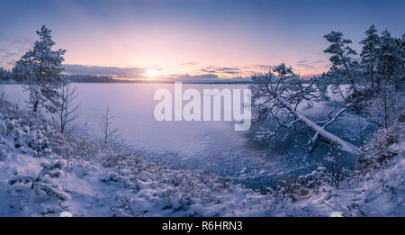 Winterlandschaft panorama Szene auf einem zugefrorenen See und verschneite Bäume bei Sonnenuntergang Stockfoto