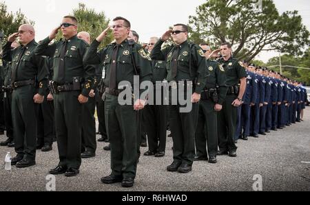 Okaloosa County Sheriff's Polizisten und Sicherheitskräfte Flieger Gruß während der Entsendung der Farben im Frieden Officers' Trauerfeier am 18. Mai in Fort Walton Beach, Fla. Die Zeremonie war gefallenen Polizisten aus dem Vorjahr zu ehren, indem ihre Namen vorlesen. Sicherheitskräfte Flieger von Eglin und Hurlburt Field besucht und an der Veranstaltung teil. Die Zeremonie ist eine von vielen Veranstaltungen während der Nationalen Polizei Woche. Stockfoto