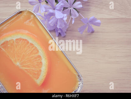 Orange Soft Cake mit blauer Blume auf hölzernen Tisch Stockfoto