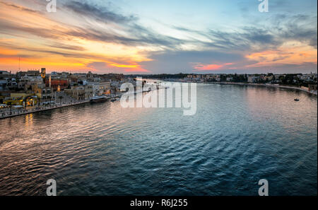 Die Promenade am Wasser füllt sich mit Touristen genießen Sie einen späten Sommer Sonnenuntergang am Hafen Stadt Brindisi Italien an der Adria in der Region Apulien Stockfoto